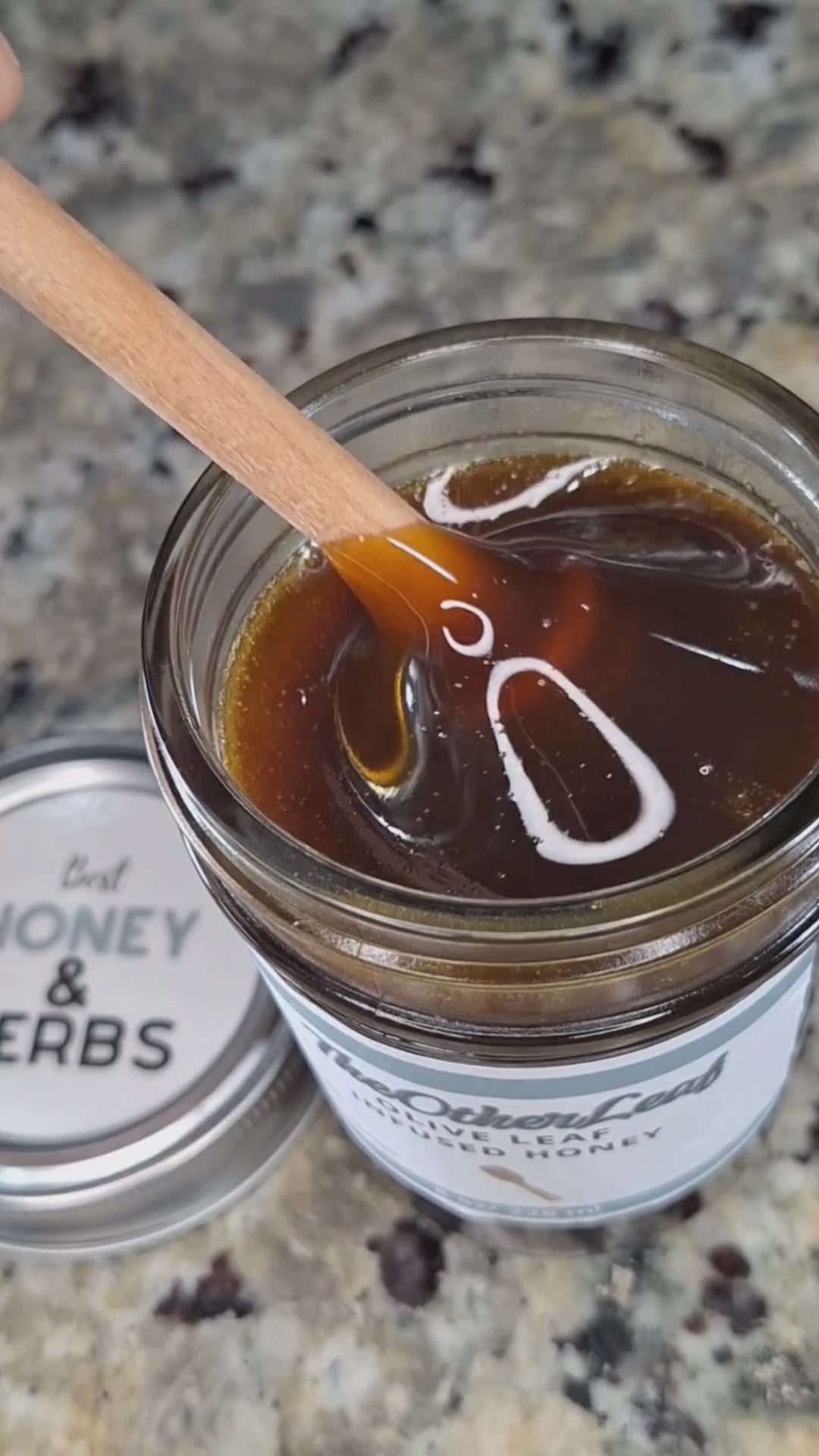  Olive leaf infused honey slowly drizzling from a honey dipper.