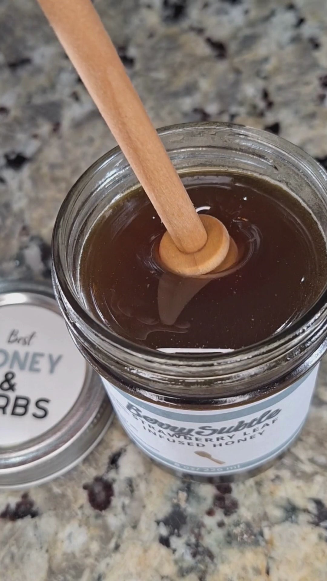  Strawberry leaf infused honey slowly drizzling from a honey dipper.