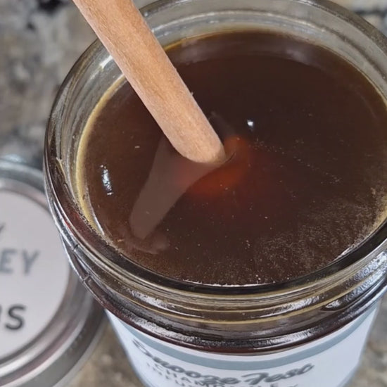 Chamomile infused honey slowly drizzling from a honey dipper.