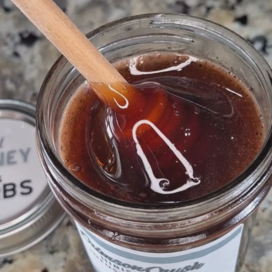  Hibiscus infused honey slowly drizzling from a honey dipper.
