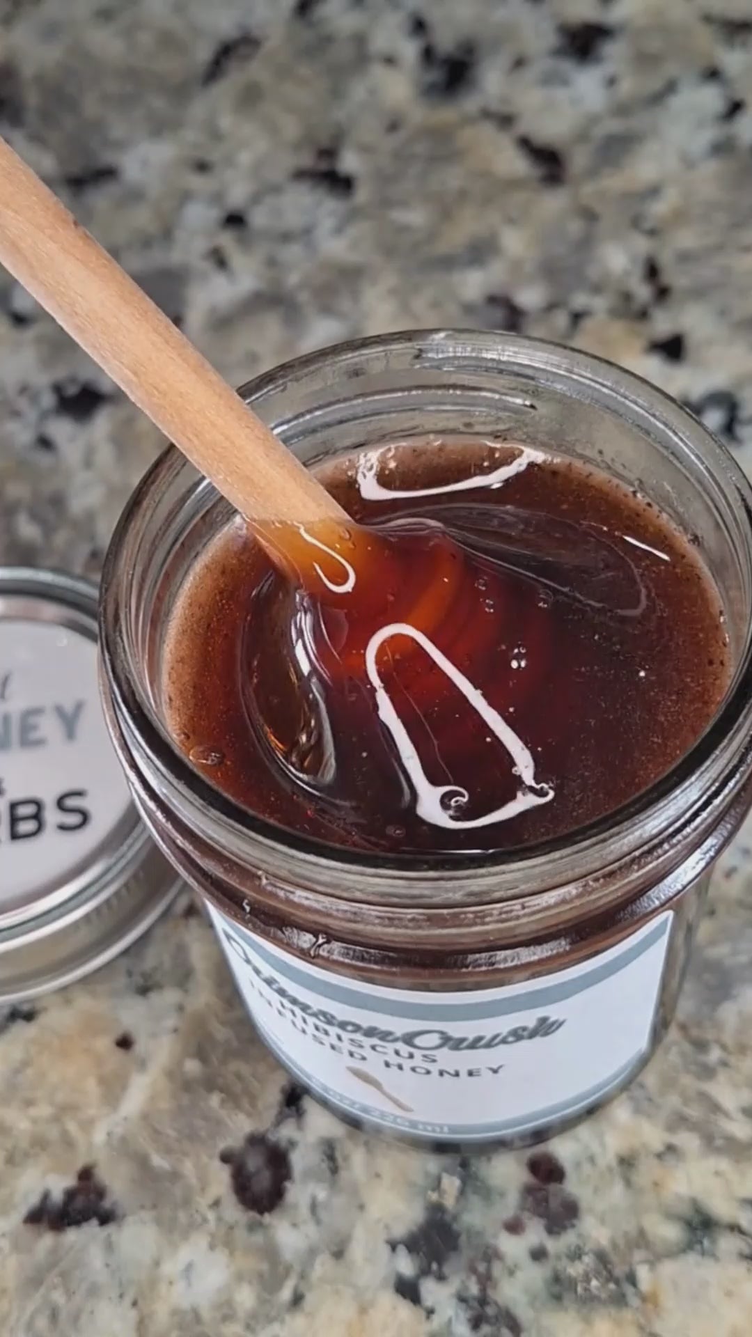  Hibiscus infused honey slowly drizzling from a honey dipper.
