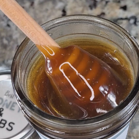  Ginkgo infused honey slowly drizzling from a honey dipper.