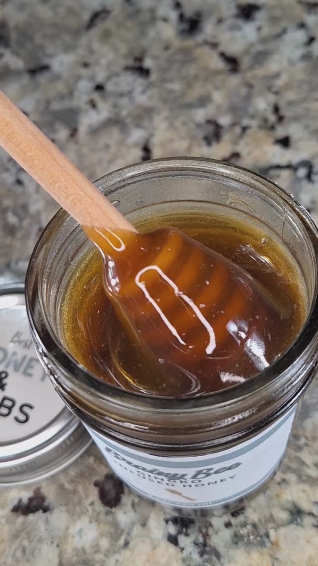  Ginkgo infused honey slowly drizzling from a honey dipper.
