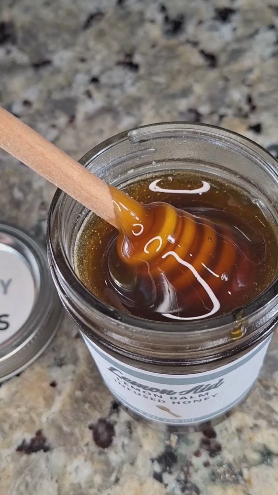  Lemon Balm infused honey slowly drizzling from a honey dipper.