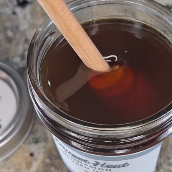 Cinnamon infused honey slowly drizzling from a honey dipper.