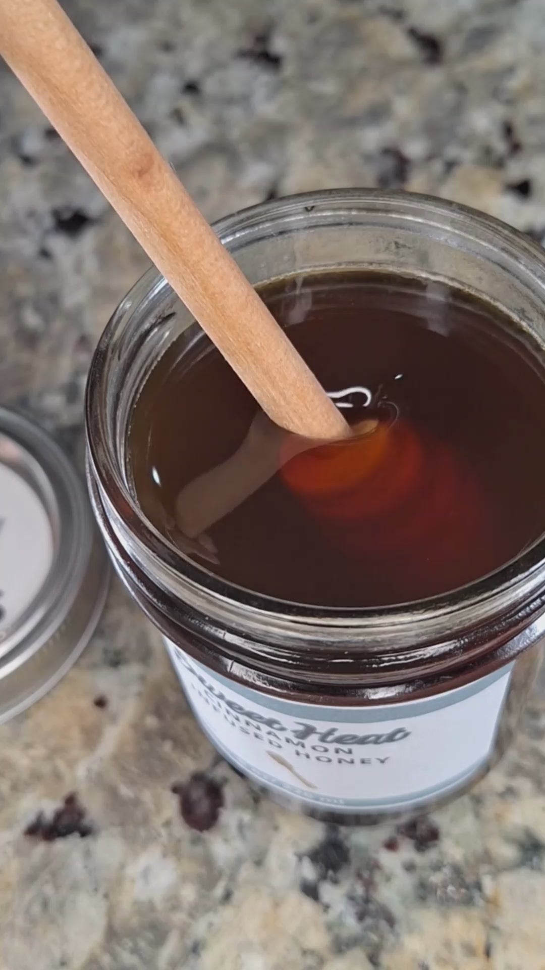 Cinnamon infused honey slowly drizzling from a honey dipper.