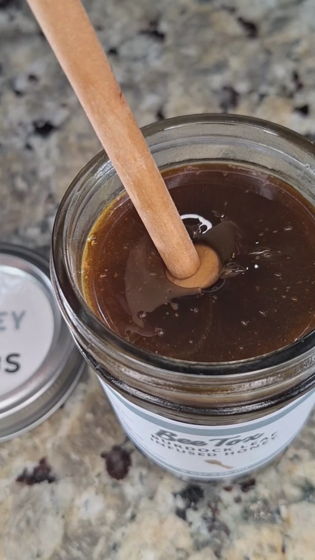 Burdock leaf infused honey slowly drizzling from a honey dipper.