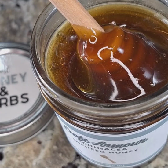  Echinacea infused honey slowly drizzling from a honey dipper.
