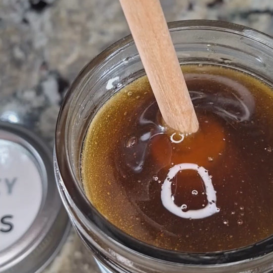 Basil infused honey slowly drizzling from a honey dipper.