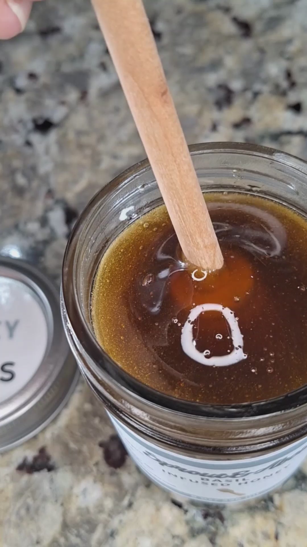 Basil infused honey slowly drizzling from a honey dipper.