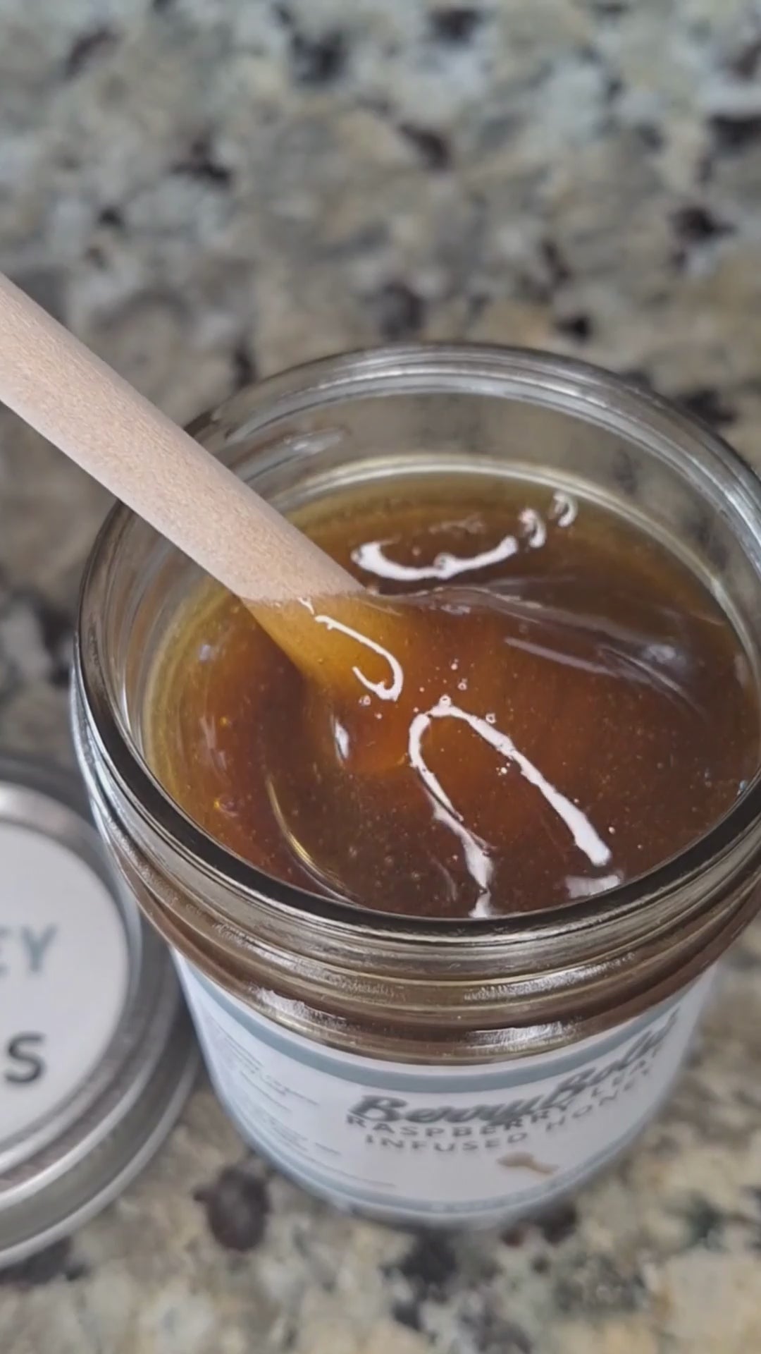  Raspberry Leaf infused honey slowly drizzling from a honey dipper.