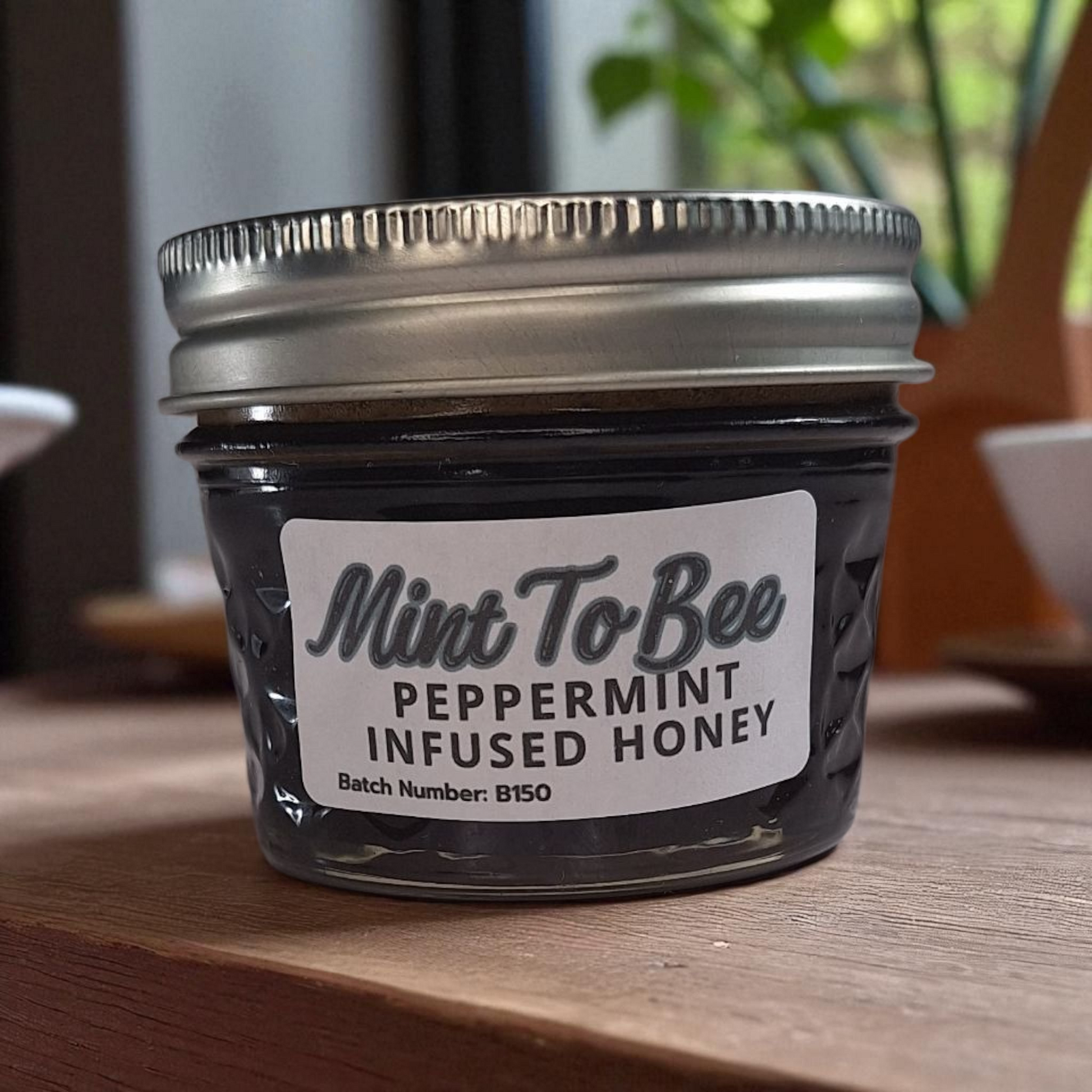 4 oz jar of raw Peppermint Leaf Infused Honey on a wooden surface, refreshing herbal sweetener for tea, baking, and holiday treats.
