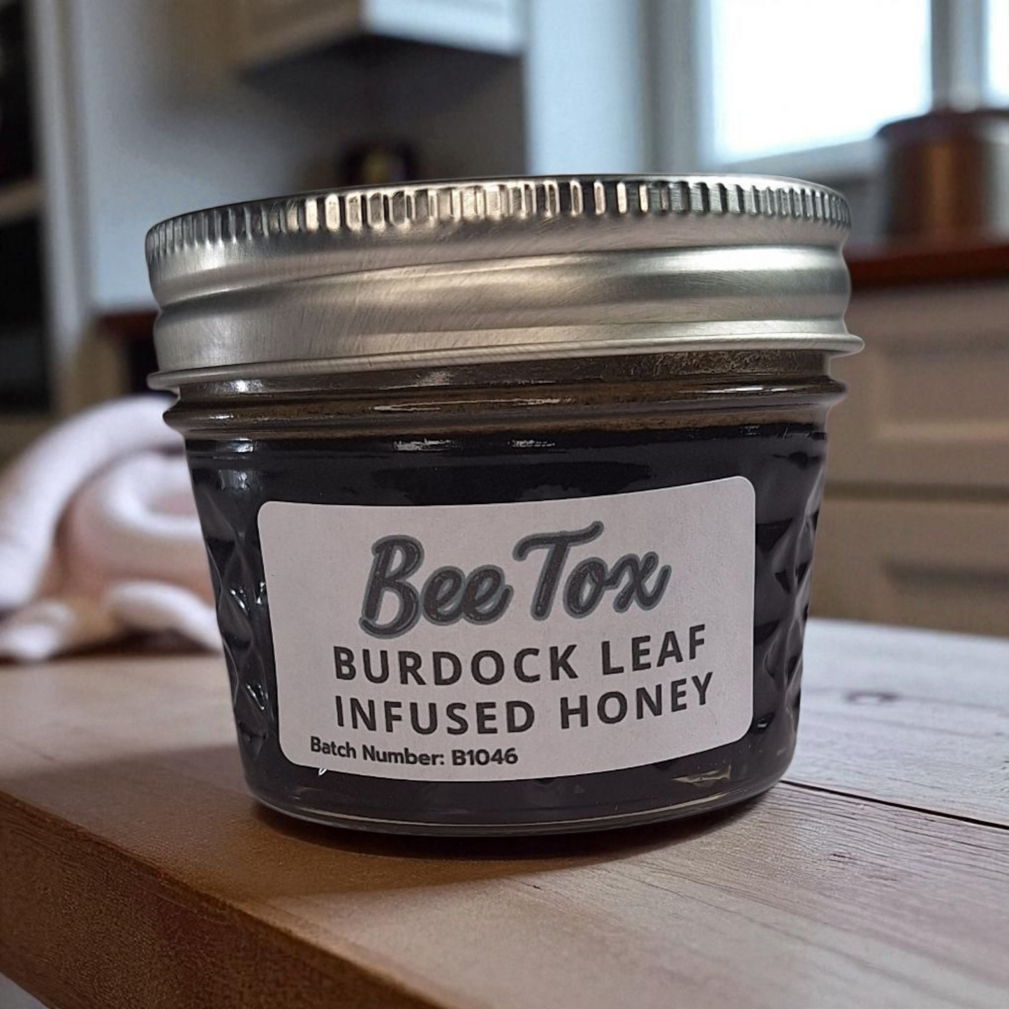 4 oz jar of raw Burdock Leaf Infused Honey on a rustic wooden surface, herbal sweetener for detox teas, tonics, and healthy recipes.