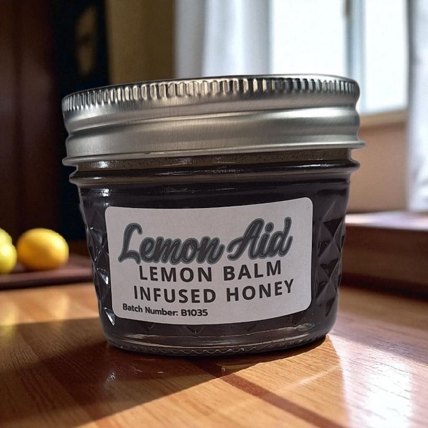 4 oz jar of raw Lemon Balm Infused Honey on a wooden surface, citrusy herbal sweetener for tea, baking, and calming recipes.
